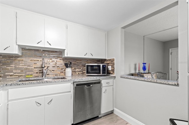 kitchen with sink, light hardwood / wood-style flooring, tasteful backsplash, white cabinetry, and stainless steel appliances