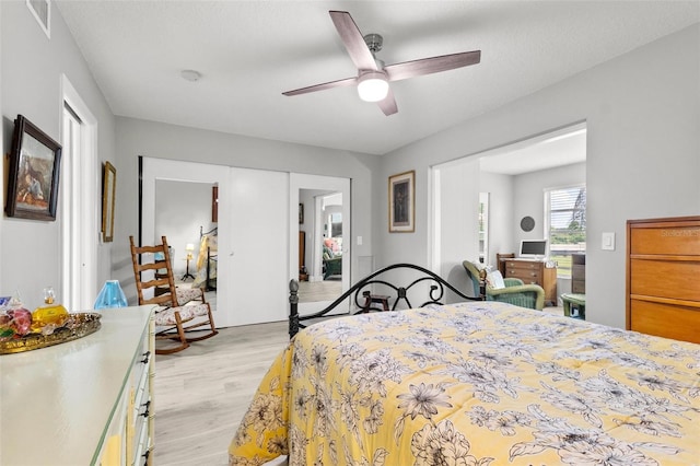 bedroom with light wood-type flooring, ceiling fan, and a closet