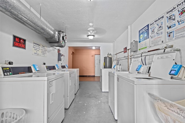 clothes washing area featuring a textured ceiling, water heater, and separate washer and dryer