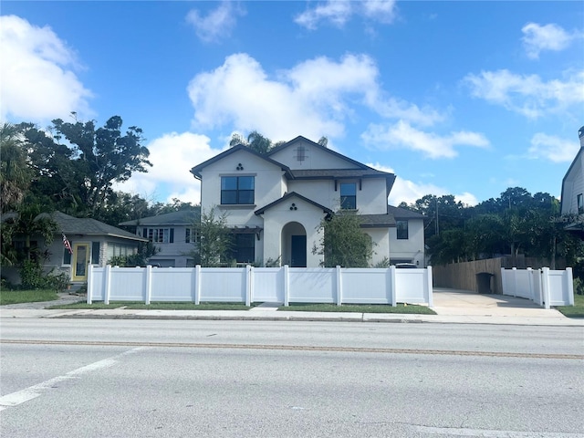 view of front of home with concrete driveway, a fenced front yard, and stucco siding