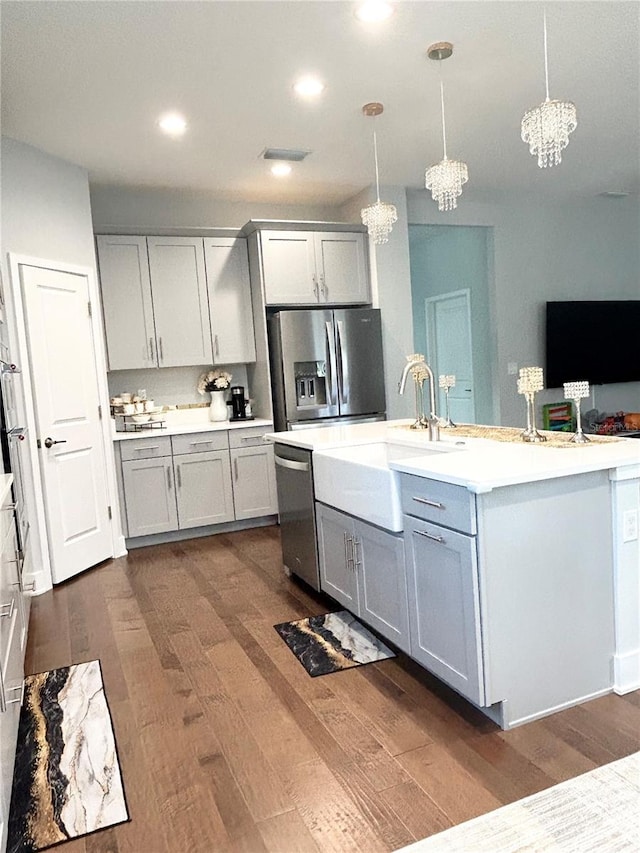 kitchen with dark wood-type flooring, gray cabinets, stainless steel appliances, light countertops, and a sink