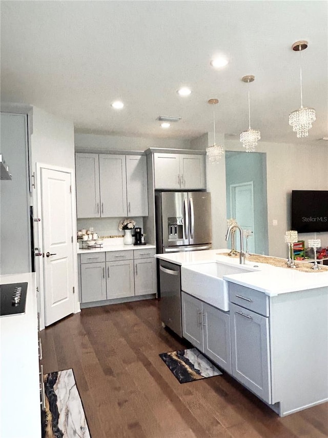 kitchen featuring dark wood-style floors, appliances with stainless steel finishes, a sink, and gray cabinetry