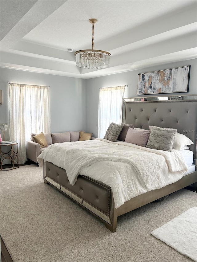 carpeted bedroom with a tray ceiling