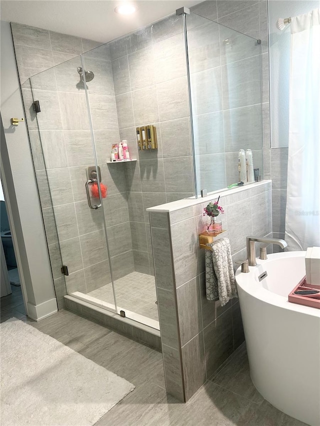 bathroom with a stall shower, a freestanding tub, and tile walls