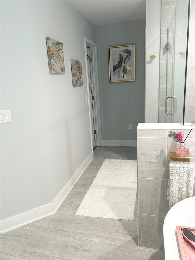 bathroom with a shower stall, baseboards, and wood finished floors