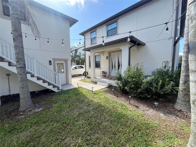 back of property with a yard and stucco siding