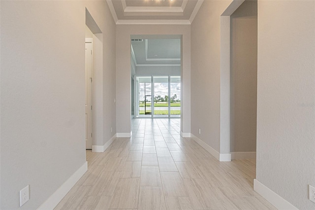 hall featuring a raised ceiling and crown molding