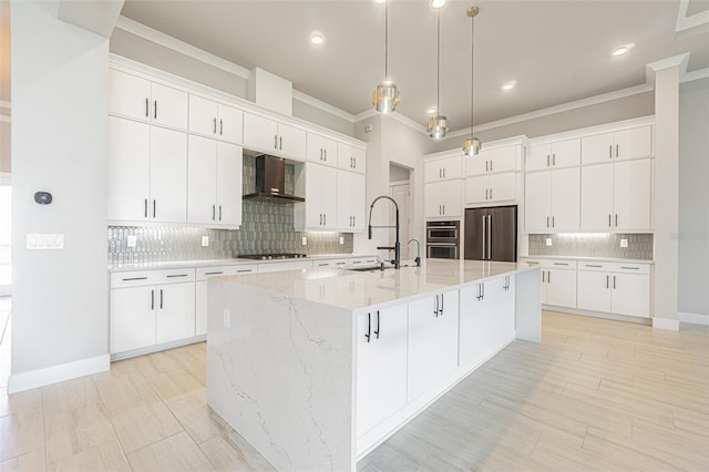 kitchen featuring appliances with stainless steel finishes, backsplash, wall chimney exhaust hood, white cabinetry, and a large island