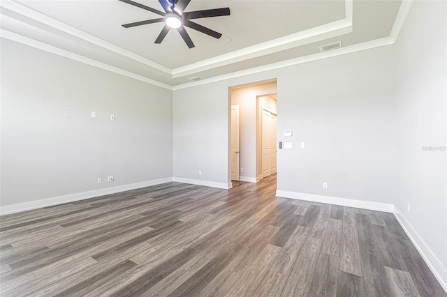 empty room featuring a raised ceiling, crown molding, dark hardwood / wood-style flooring, and ceiling fan