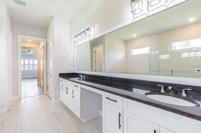 bathroom featuring a wealth of natural light, a shower with door, vanity, and ceiling fan