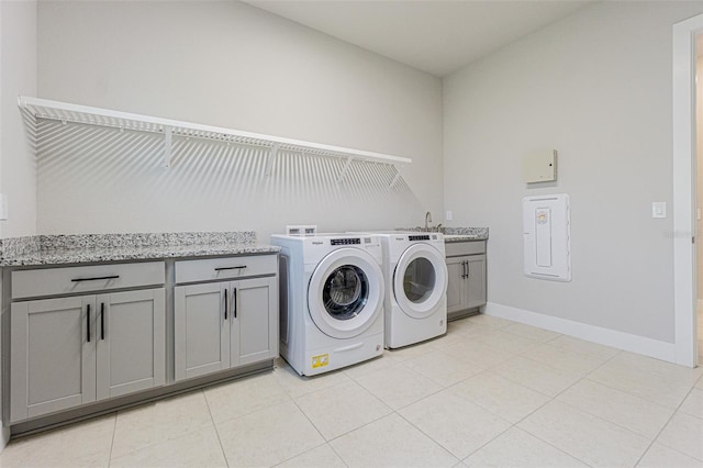 clothes washing area featuring washing machine and dryer, light tile patterned floors, and cabinets