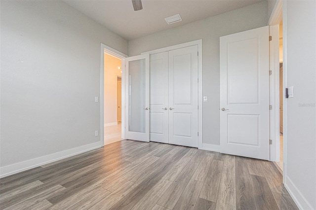 unfurnished bedroom featuring hardwood / wood-style floors, ceiling fan, and a closet