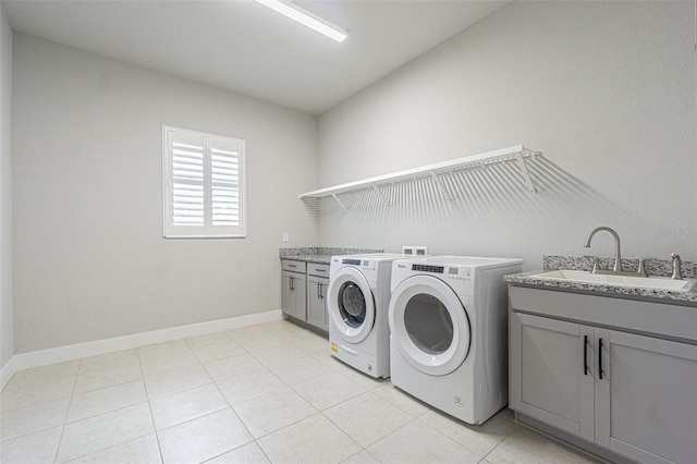 clothes washing area featuring cabinets, light tile patterned floors, washer and clothes dryer, and sink