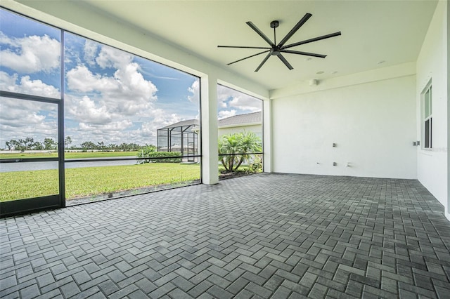 unfurnished sunroom featuring ceiling fan and a water view