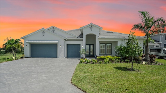 view of front of home featuring a lawn, french doors, and a garage