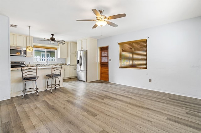 kitchen with visible vents, appliances with stainless steel finishes, light wood-style floors, open floor plan, and a kitchen breakfast bar