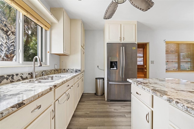 kitchen featuring light wood finished floors, plenty of natural light, stainless steel refrigerator with ice dispenser, and a sink