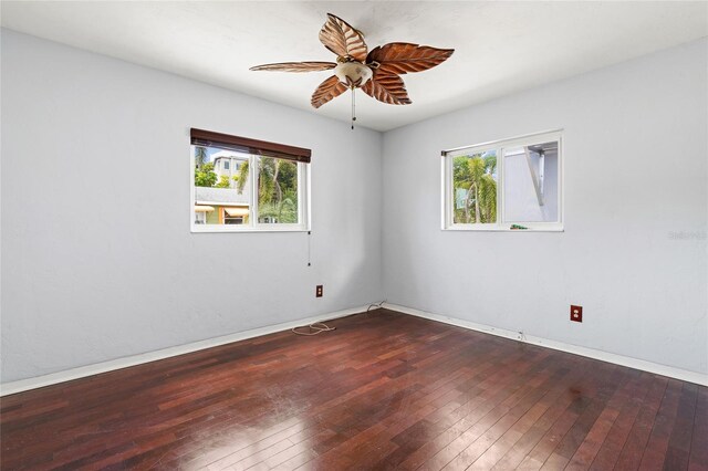 empty room with ceiling fan, a healthy amount of sunlight, and dark hardwood / wood-style flooring