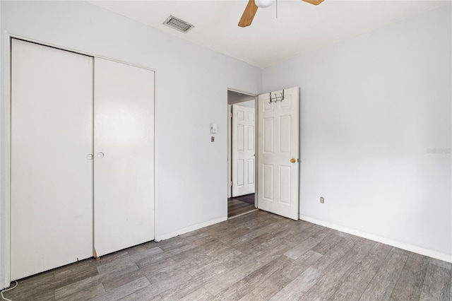 unfurnished bedroom featuring a closet, visible vents, a ceiling fan, wood finished floors, and baseboards