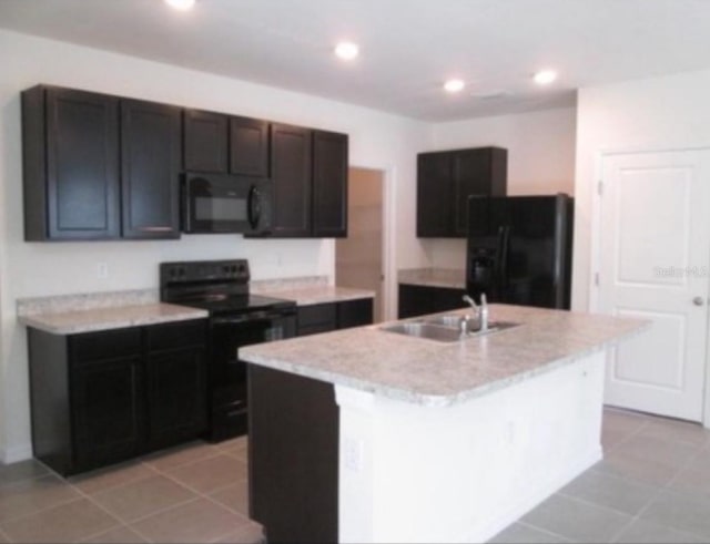 kitchen with a kitchen island with sink, light tile patterned floors, sink, and black appliances