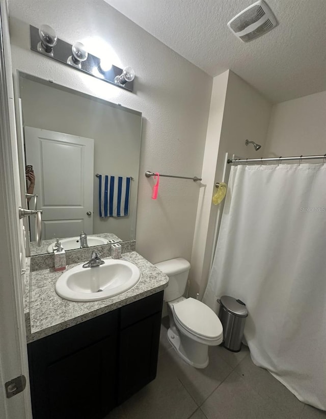 bathroom featuring a shower with shower curtain, vanity, tile patterned flooring, a textured ceiling, and toilet