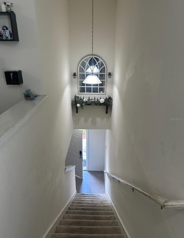 stairway featuring a high ceiling and tile patterned floors