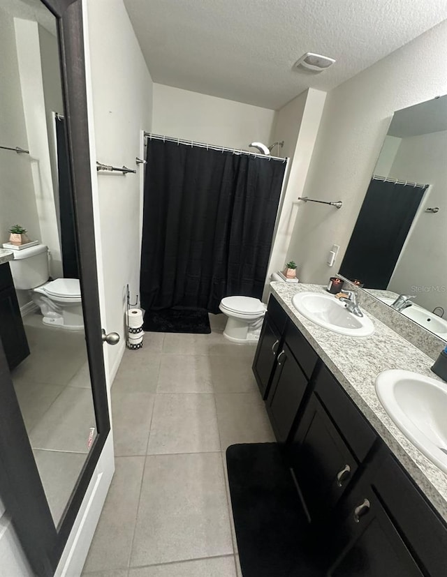 bathroom with a shower with shower curtain, vanity, tile patterned floors, a textured ceiling, and toilet