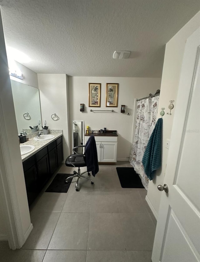 bathroom featuring a textured ceiling, vanity, walk in shower, and tile patterned floors