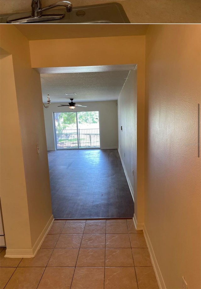 corridor with a textured ceiling and light wood-type flooring