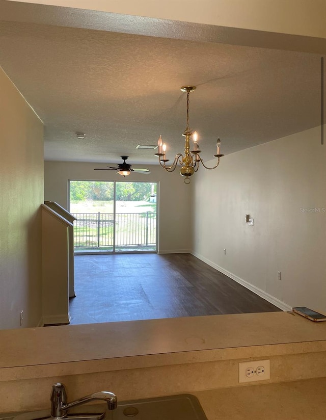 spare room with ceiling fan with notable chandelier, a textured ceiling, and hardwood / wood-style flooring