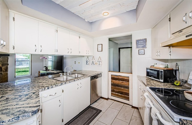 kitchen featuring white cabinets, light tile patterned floors, appliances with stainless steel finishes, sink, and a raised ceiling