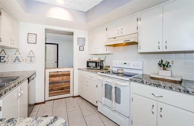 kitchen featuring light tile patterned floors, stainless steel appliances, white cabinetry, a raised ceiling, and tasteful backsplash