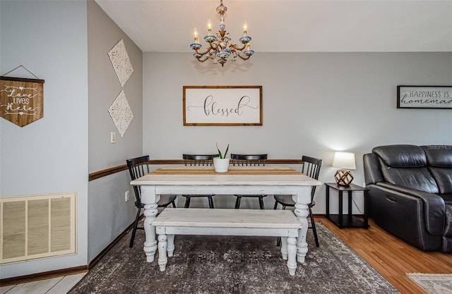 dining area with baseboards, visible vents, an inviting chandelier, and wood finished floors