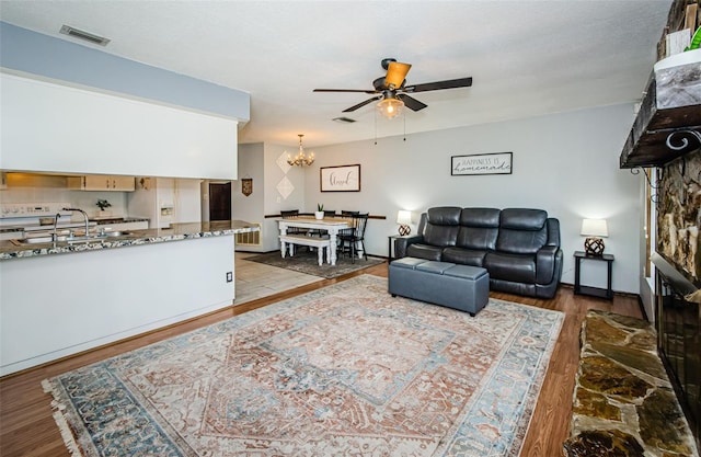 living room featuring sink, ceiling fan with notable chandelier, and wood-type flooring