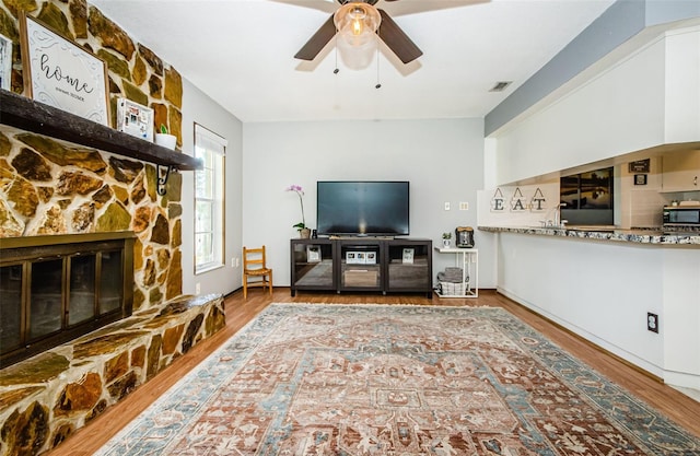 living room with a fireplace, hardwood / wood-style flooring, and ceiling fan