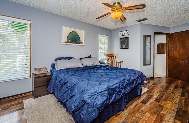 bedroom featuring dark wood-type flooring, ceiling fan, and a textured ceiling