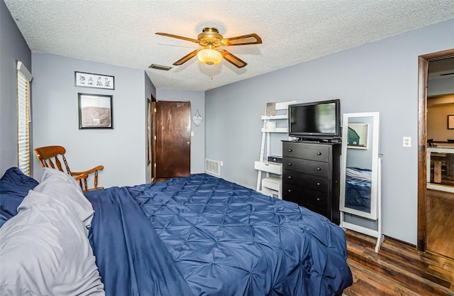 bedroom with dark hardwood / wood-style flooring, ceiling fan, and a textured ceiling