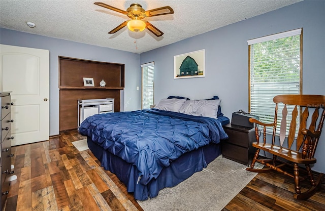 bedroom with ceiling fan, a textured ceiling, and dark wood-type flooring