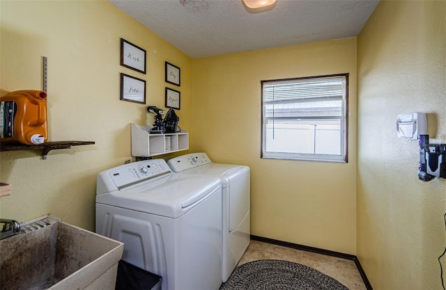 clothes washing area featuring washing machine and clothes dryer, sink, light tile patterned floors, and a textured ceiling