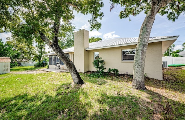 rear view of property featuring a lawn, a patio, metal roof, fence, and stucco siding