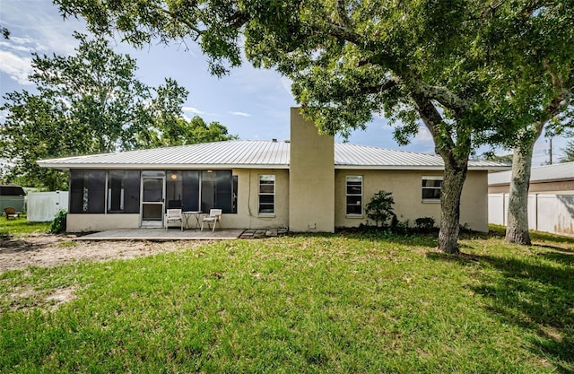 back of property featuring a sunroom, fence, metal roof, and a yard