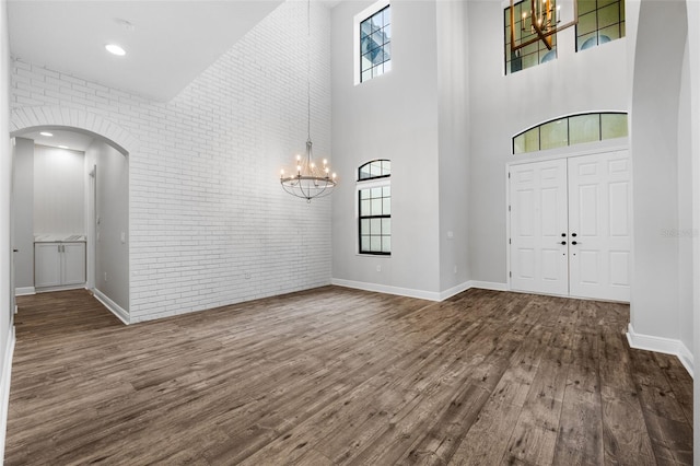 entrance foyer with a towering ceiling, dark hardwood / wood-style floors, and brick wall