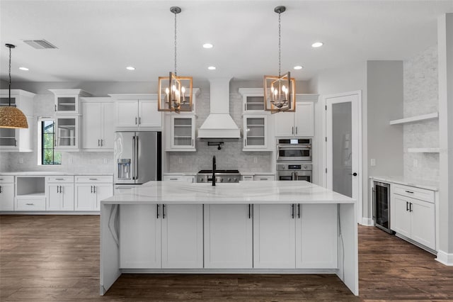 kitchen with white cabinetry, premium range hood, light stone counters, and stainless steel appliances