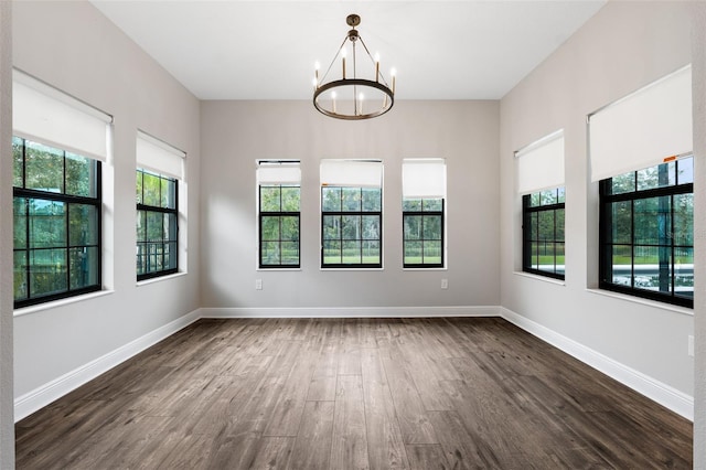 unfurnished room featuring dark wood-type flooring, a chandelier, and a healthy amount of sunlight