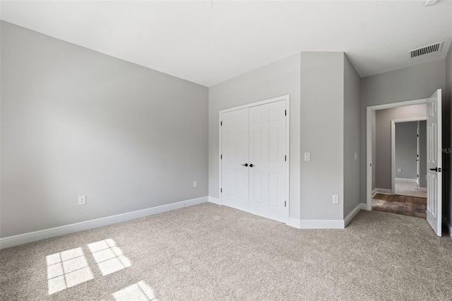 unfurnished bedroom with light colored carpet and a closet