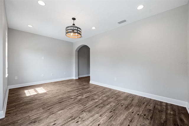 empty room featuring dark wood-type flooring and an inviting chandelier