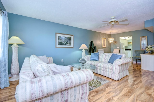 living room with a textured ceiling, light hardwood / wood-style flooring, and ceiling fan