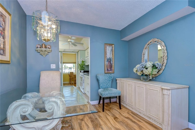 interior space with ceiling fan with notable chandelier, light hardwood / wood-style floors, and a textured ceiling