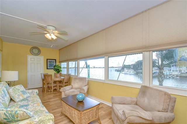 living room featuring vaulted ceiling, a water view, hardwood / wood-style floors, and ceiling fan