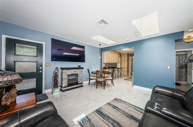 tiled living room featuring a skylight and a stone fireplace